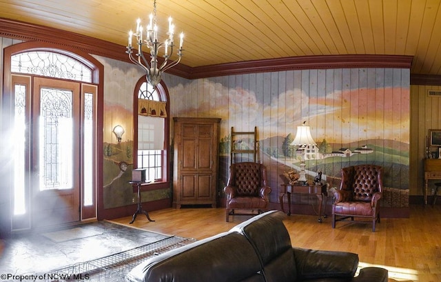 foyer entrance featuring light wood-type flooring, an inviting chandelier, a healthy amount of sunlight, and wooden walls