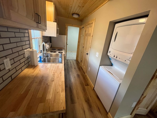 kitchen featuring brick wall, sink, stacked washer / dryer, wooden ceiling, and light hardwood / wood-style floors