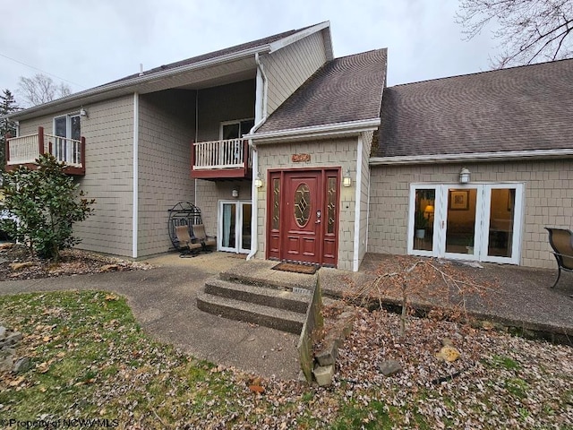 view of front facade featuring french doors, a balcony, and a patio