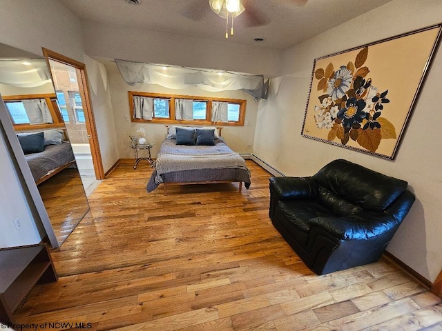 bedroom featuring a baseboard radiator, ceiling fan, light hardwood / wood-style flooring, and multiple windows