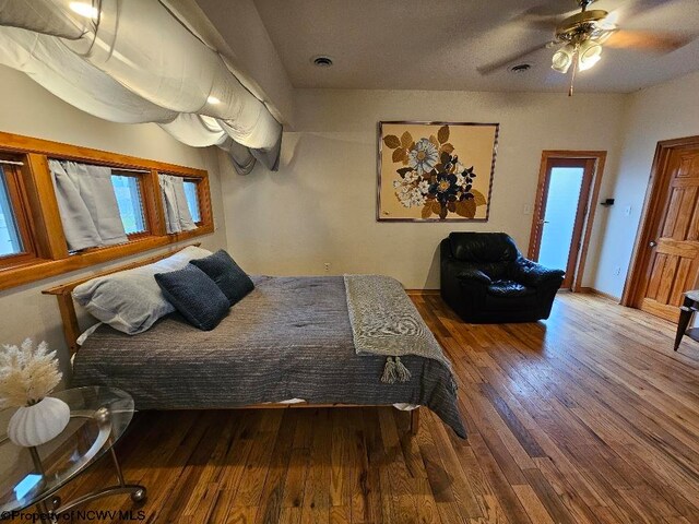 bedroom with ceiling fan, hardwood / wood-style flooring, and multiple windows