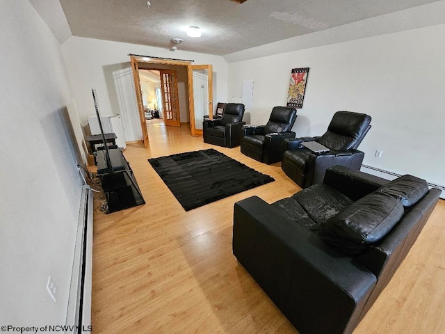 living room with baseboard heating, a textured ceiling, french doors, and light hardwood / wood-style flooring