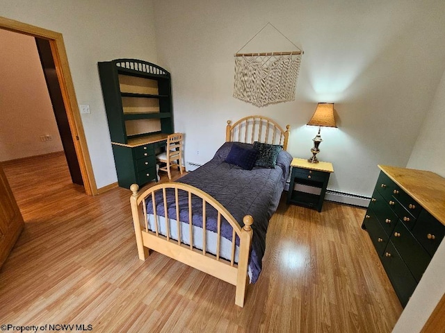 bedroom with a baseboard radiator and light hardwood / wood-style flooring