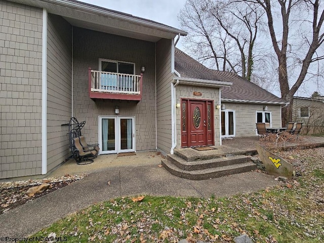 view of front facade with a balcony, french doors, and a patio area