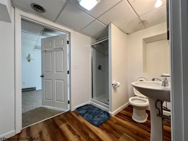 bathroom featuring hardwood / wood-style floors, toilet, a shower with shower door, and a paneled ceiling