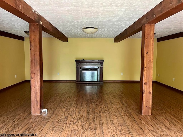 unfurnished living room featuring dark hardwood / wood-style flooring, beamed ceiling, and a textured ceiling