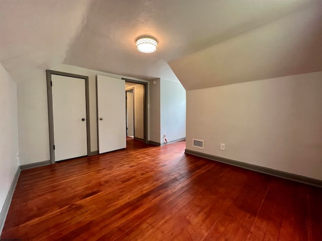 bonus room with dark wood-type flooring and vaulted ceiling