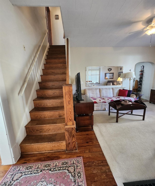 stairs featuring ceiling fan and dark hardwood / wood-style floors