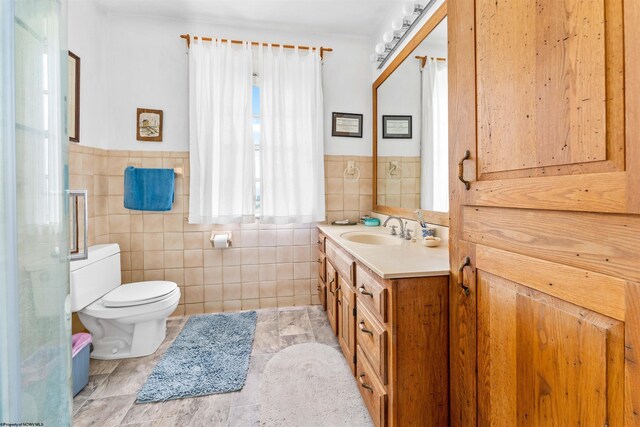 bathroom with tile walls, tile flooring, toilet, and vanity