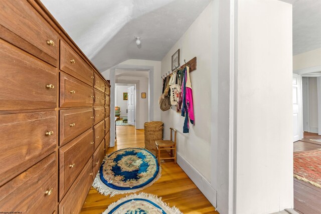 hallway featuring light hardwood / wood-style floors and vaulted ceiling