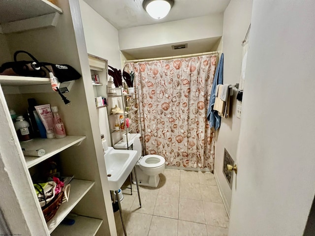 bathroom featuring toilet, tile flooring, and sink