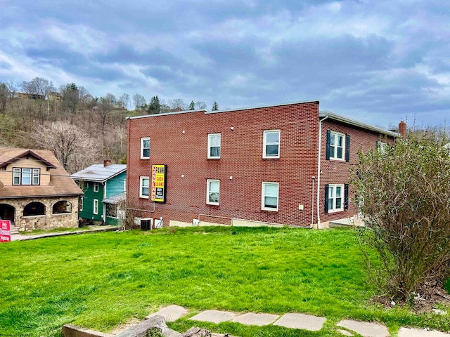 rear view of house featuring a yard and central AC unit