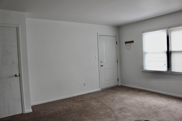 spare room featuring plenty of natural light and dark colored carpet