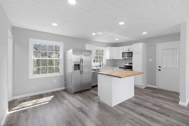 kitchen featuring a kitchen island, hardwood / wood-style floors, stainless steel appliances, and white cabinetry