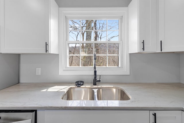 kitchen with sink, white cabinetry, and light stone counters