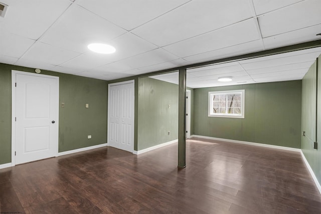 basement featuring a paneled ceiling and dark hardwood / wood-style floors