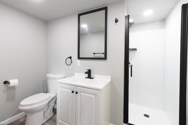 bathroom with toilet, vanity, hardwood / wood-style flooring, and tiled shower