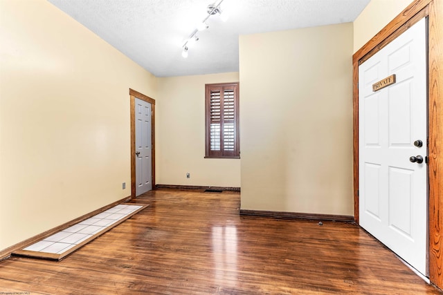 foyer entrance with track lighting, a textured ceiling, and dark wood-type flooring