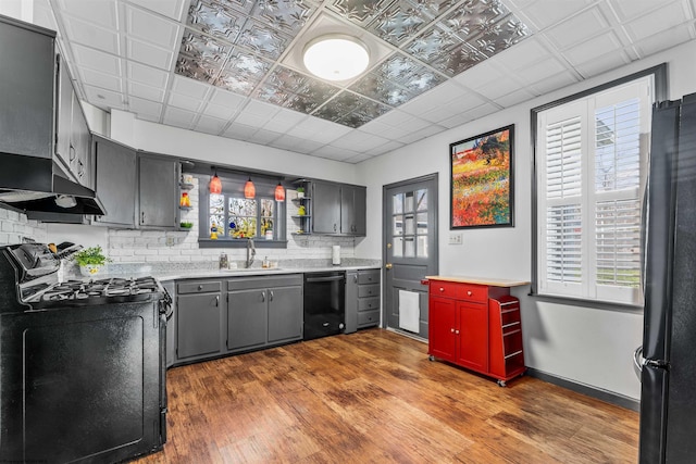 kitchen with plenty of natural light, tasteful backsplash, black appliances, and hardwood / wood-style flooring