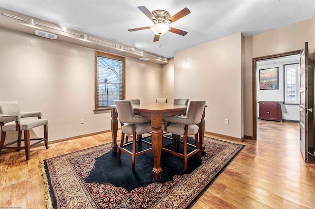 dining room featuring light hardwood / wood-style flooring, ceiling fan, track lighting, and a textured ceiling