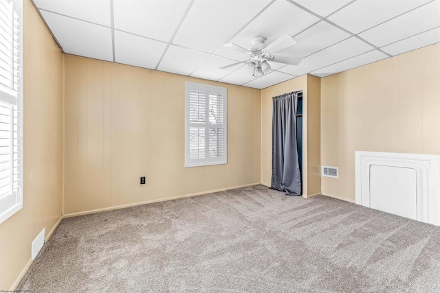 carpeted spare room featuring ceiling fan and a paneled ceiling