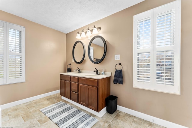 bathroom with a textured ceiling, vanity with extensive cabinet space, and tile flooring