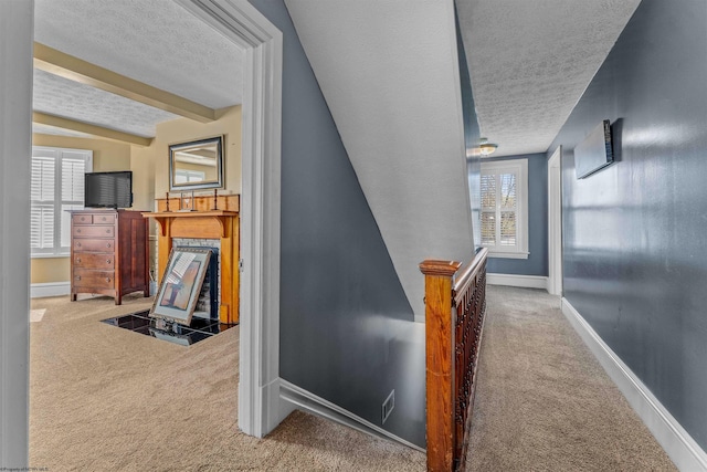 corridor featuring light carpet, a textured ceiling, and beamed ceiling