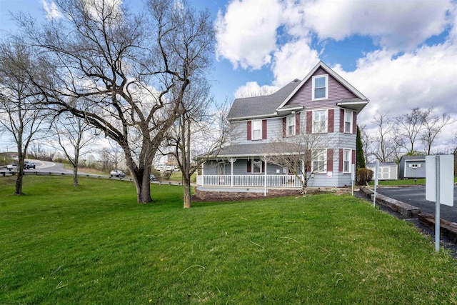 view of front facade featuring covered porch, a front lawn, and an outdoor structure