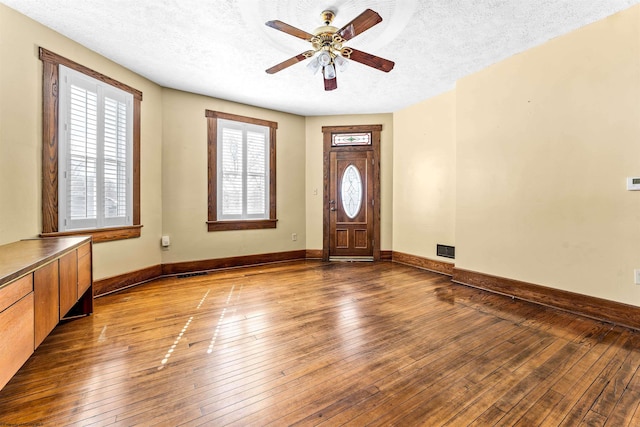 entrance foyer with ceiling fan, a textured ceiling, and dark wood-type flooring