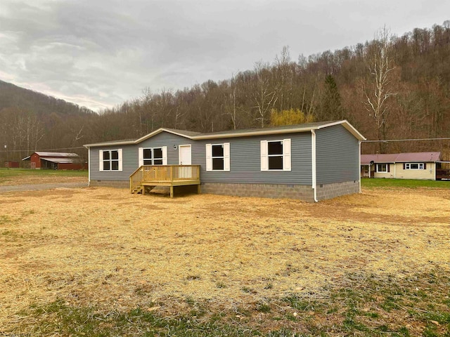 view of front of home featuring a front lawn and a wooden deck