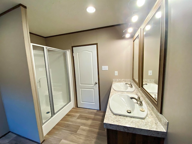 bathroom featuring a shower with shower door, wood-type flooring, crown molding, and vanity