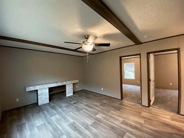 unfurnished bedroom featuring a textured ceiling, beamed ceiling, wood-type flooring, ceiling fan, and ornamental molding