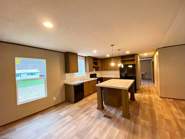 kitchen with a wealth of natural light, a center island, sink, and light hardwood / wood-style floors