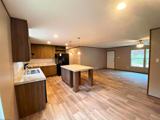 kitchen with decorative light fixtures, light hardwood / wood-style floors, sink, black refrigerator, and ceiling fan