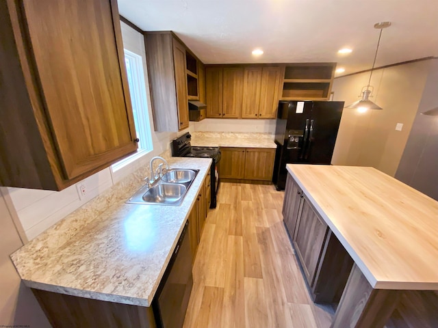 kitchen with black appliances, pendant lighting, sink, and light wood-type flooring