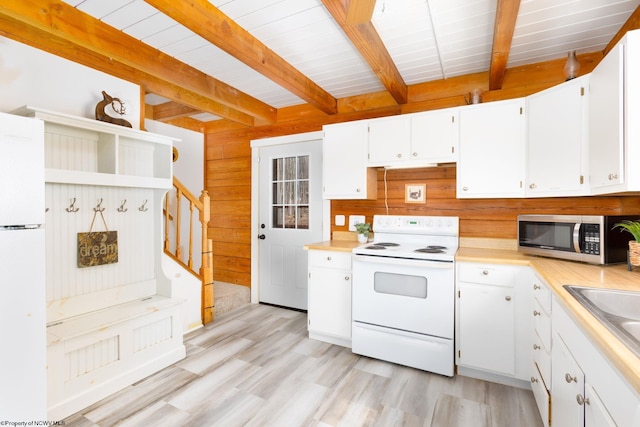 kitchen featuring wooden walls, white appliances, beam ceiling, white cabinetry, and light hardwood / wood-style flooring