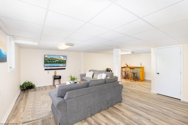 living room with light hardwood / wood-style floors and a drop ceiling