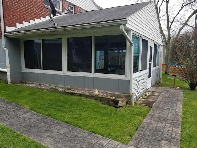 view of property exterior featuring a sunroom and a lawn