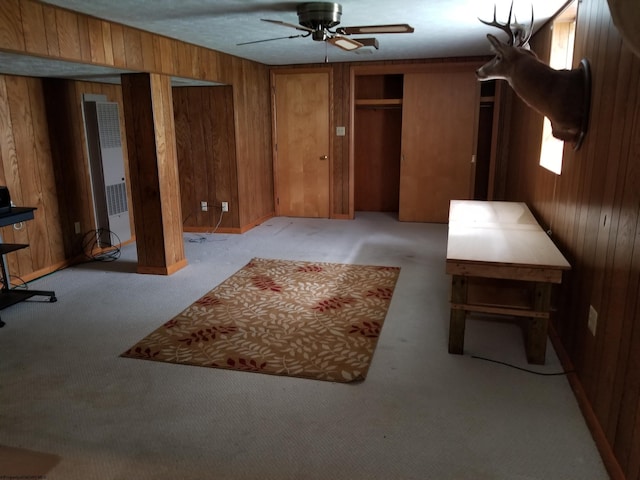 interior space featuring ceiling fan, light colored carpet, and wood walls