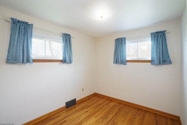 spare room featuring hardwood / wood-style floors and plenty of natural light