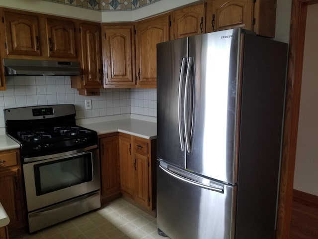 kitchen featuring appliances with stainless steel finishes, tasteful backsplash, and wall chimney range hood