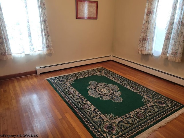 empty room featuring a baseboard radiator and light hardwood / wood-style flooring