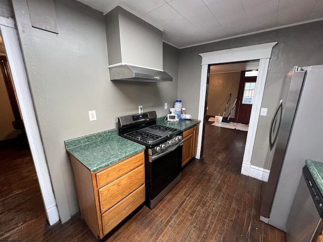 kitchen with wall chimney exhaust hood, dark hardwood / wood-style flooring, gas range, and stainless steel refrigerator