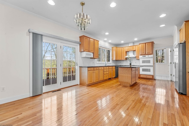 kitchen with a center island, pendant lighting, stainless steel appliances, tasteful backsplash, and light hardwood / wood-style floors