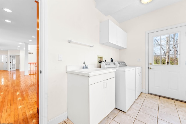 laundry area with cabinets, sink, light hardwood / wood-style floors, hookup for a washing machine, and washing machine and dryer