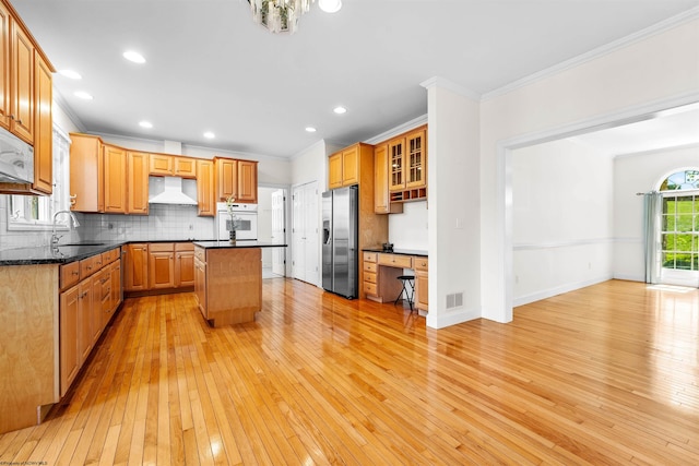 kitchen featuring white appliances, light wood-type flooring, sink, a kitchen island, and tasteful backsplash