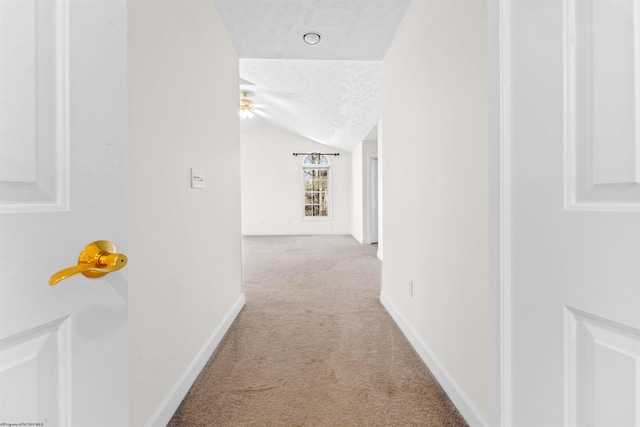 corridor with lofted ceiling, light carpet, and a textured ceiling