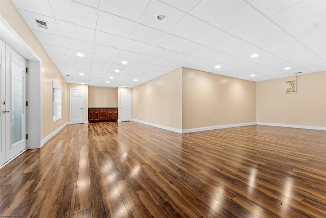 basement with a drop ceiling and dark wood-type flooring