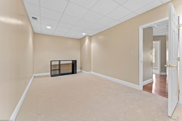 interior space featuring light colored carpet, a fireplace, and a paneled ceiling