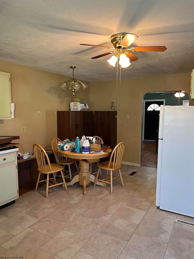 tiled dining area with ceiling fan and a textured ceiling